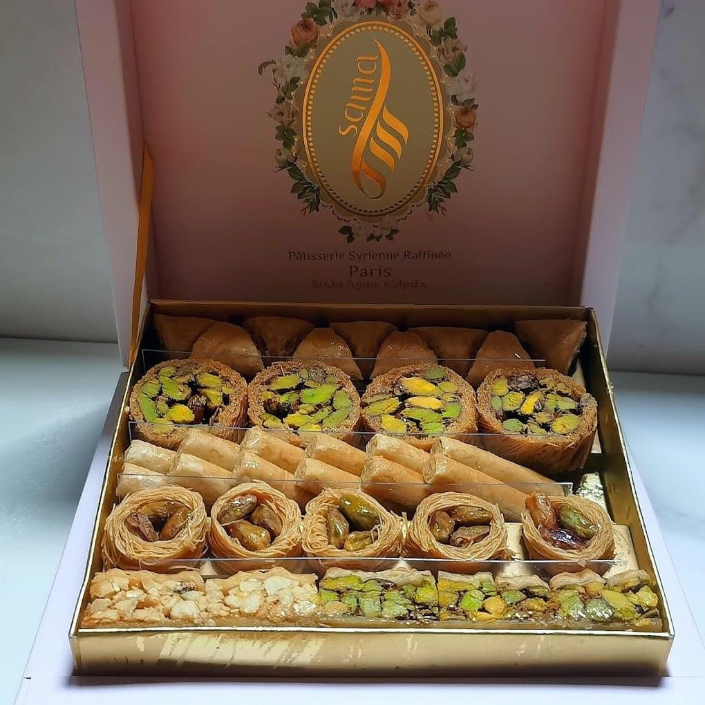 Coffret Sama ouvert sur un assortiment de baklawa à la pistache : triangles, rouleaux, nids et barres