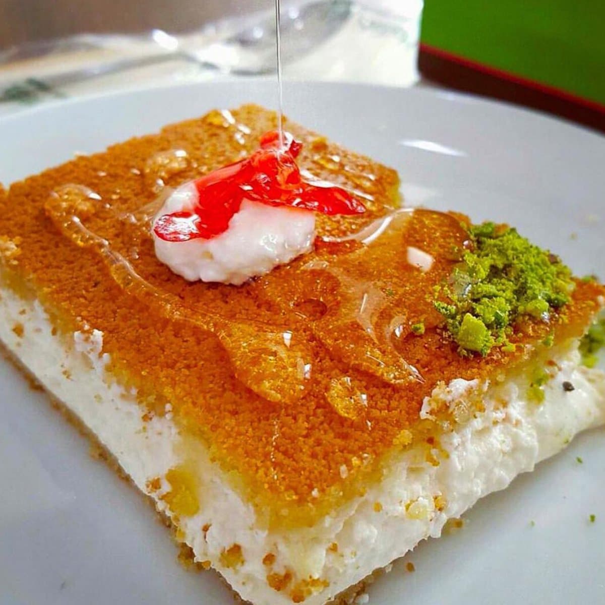 Part de knafeh à la croûte dorée, arrosée de sirop, avec de la pistache